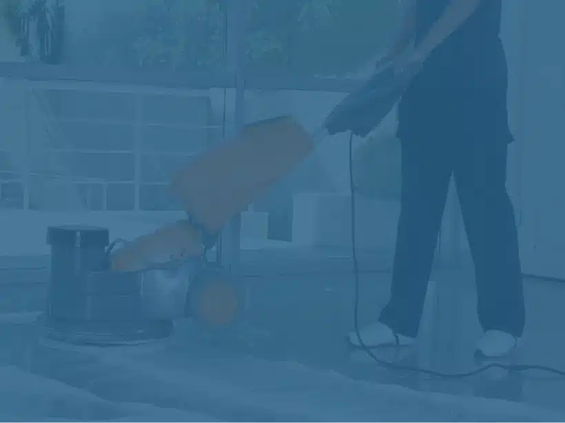 Floor image of a woman cleaning a tiled floor with a yellow industrial cleaning machine.